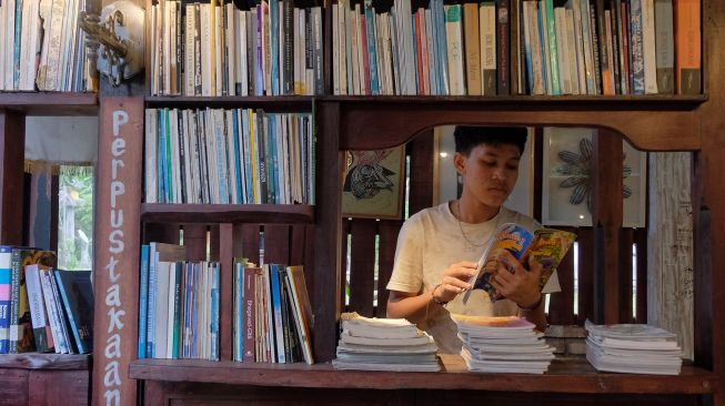 Seorang anak membaca buku di perpustakaan Dusun Senja, Desa Candikusuma, Jembrana, Bali, Sabtu (23/7/2022). [ANTARA FOTO/Nyoman Hendra Wibowo/wsj]
