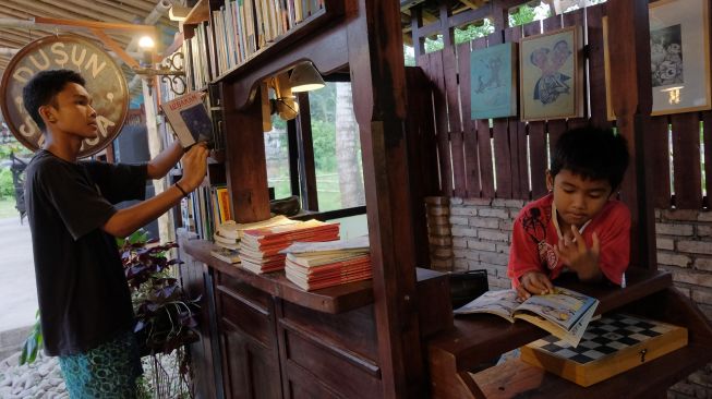 Anak-anak membaca buku di perpustakaan Dusun Senja, Desa Candikusuma, Jembrana, Bali, Sabtu (23/7/2022). [ANTARA FOTO/Nyoman Hendra Wibowo/wsj]