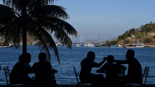 Siluet wisatawan mancanegara menikmati santapan dengan pemandangan perairan Labuan Bajo di Kabupaten Manggarai Barat, NTT, Sabtu (23/7/2022). [ANTARA FOTO/Indrianto Eko Suwarso/wsj]