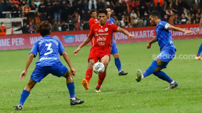 Pesepakbola Persija Jakarta Hanif Syahbandi (tengah) berusaha melewati pemain Chonburi FC saat laga persahabatan dalam rangka Grand Launching Jakarta International Stadium (JIS) di Tanjung Priok, Jakarta Utara, Minggu (24/7/2022). [Suara.com/Alfian Winanto]