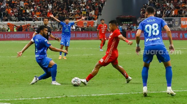 Pesepakbola Persija Jakarta Taufik Hidayat berebut bola dengan pemain Chonburi FC  saat laga persahabatan dalam rangka Grand Launching Jakarta International Stadium (JIS) di Tanjung Priok, Jakarta Utara, Minggu (24/7/2022). [Suara.com/Alfian Winanto]