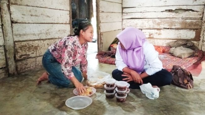 Rumiatun (berjilbab), pegiat sosial, sedang berbincang dengan Apriliyani, anak penyandang disabilitas di Lampung Timur. [Dok Rumiatun] 