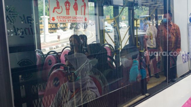 Penumpang menaiki bus pink Transjakarta di Halte Pasar Baru, Jakarta Pusat, Rabu (27/7/2022). [Suara.com/Alfian Winanto]