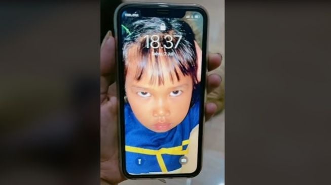 Tangkapan layar walpaper sebuah handphone yang menampilkan wajah anak kecil sedang marah. (TikTok/@ditanganu)