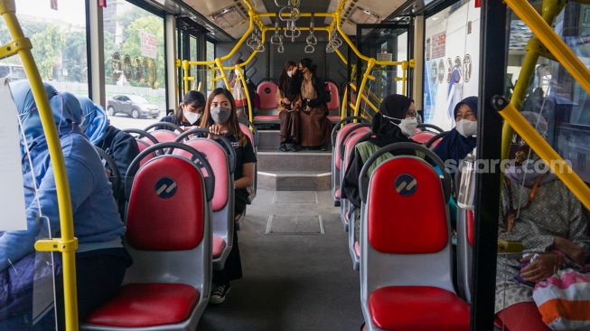 Penumpang menaiki bus pink Transjakarta di Halte Pasar Baru, Jakarta Pusat, Rabu (27/7/2022). [Suara.com/Alfian Winanto]