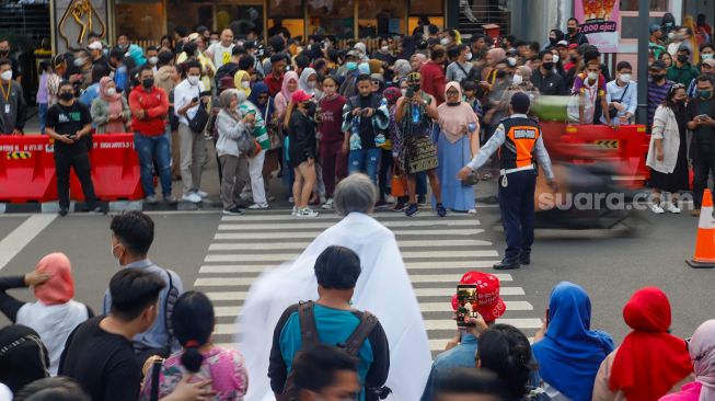 Petugas mengatur lalu lintas di lokasi peragaan busana Citayam Fashion Week di kawasan Dukuh Atas, Jakarta Pusat, Rabu (27/7/2022). [Suara.com/Alfian Winanto]