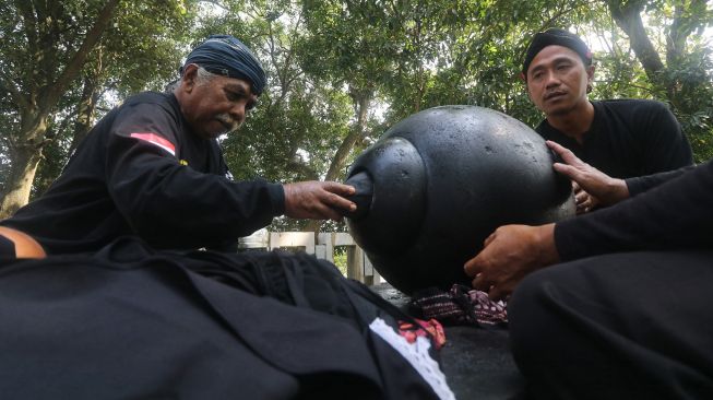 Petugas menggunakan kain milik peziarah untuk membersihkan batu manik di petilasan Sri Aji Jayabaya Desa Menang, Kediri, Jawa Timur, Jumat (29/7/2022).  ANTARA FOTO/Prasetia Fauzani