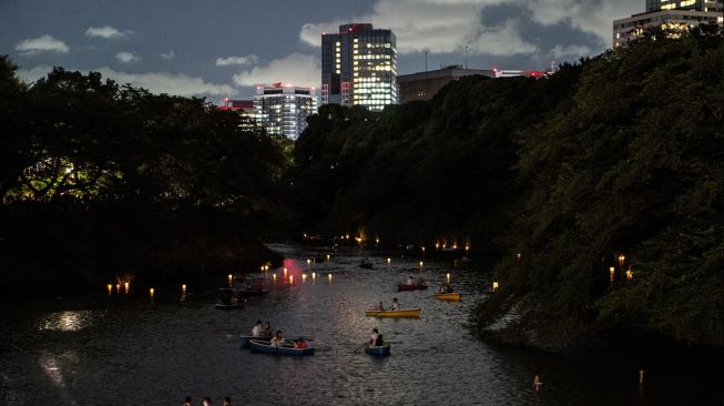 Orang-orang berlayar dengan perahu dayung saat festival lentera terapung di Chidorigafuchi, Tokyo, Jepang, Jumat (29/7/2022). [Philip FONG / AFP]