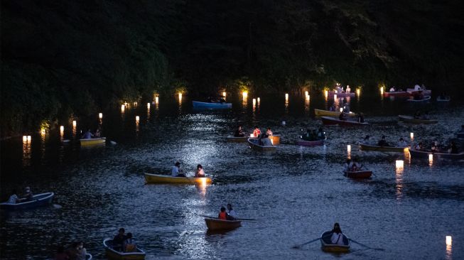 Orang-orang berlayar dengan perahu dayung saat festival lentera terapung di Chidorigafuchi, Tokyo, Jepang, Jumat (29/7/2022). [Philip FONG / AFP]