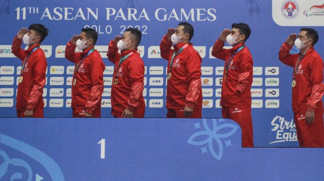 Pebulu tangkis beregu Indonesia melakukan penghormatan kepada bendera Merah Putih saat penyerahan medali emas ASEAN Para Games 2022 di Edutorium UMS, Sukoharjo, Jawa Tengah, Minggu (31/7/2022). [ANTARA FOTO/Hendra Nurdiyansyah/tom]