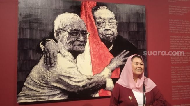 eni Wahid berfoto di depan lukisan Gus Dur dan Buya Syafii Maarif karya G. Djoko Susilo. [Suara.com/ Angga Haksoro Ardi]