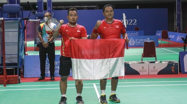 Pebulutangkis Indonesia, Hary Susanto bersama rekannya, Hafizh Briliansyah (kanan) memegang bendera Merah Putih usai mengalahkan pebulutangkis Thailand dalam final bulutangkis beregu ASEAN Para Games 2022 di Edutorium UMS, Sukoharjo, Jawa Tengah, Minggu (31/7/2022). [ANTARA FOTO/Hendra Nurdiyansyah]