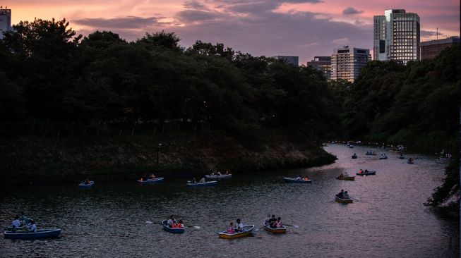 Orang-orang berlayar dengan perahu dayung saat festival lentera terapung di Chidorigafuchi, Tokyo, Jepang, Jumat (29/7/2022). [Philip FONG / AFP]
