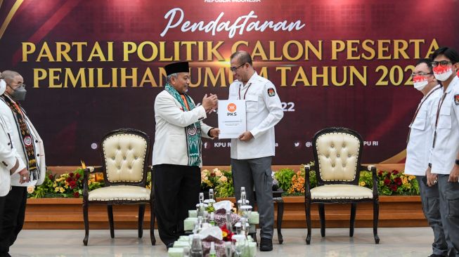 Ketua Komisi Pemilihan Umum (KPU) Hasyim Asy'ari (kanan) berjabat tangan usai menerima berkas pendaftaran dari Presiden Partai Keadilan Sejahtera (PKS) Ahmad Syaikhu (kiri) saat Pendaftaran Partai Politik Calon Peserta Pemilu tahun 2024 di Kantor KPU, Jakarta, Senin (1/8/2022). [ANTARA FOTO/M Risyal Hidayat/nym]
