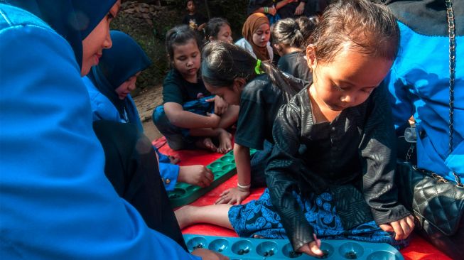 Anak Suku Baduy bermain congklak di Kampung Kaduketug, Lebak, Banten, Senin (1/8/2022). [ANTARA FOTO/Muhammad Bagus Khoirunas/nym]