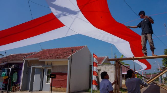 Sejumlah warga bergotong royong memasang kain merah putih di Perumahan Mutiara Tragung, Kecamatan Kandeman, Kabupaten Batang, Jawa Tengah, Senin (1/8/2022). [ANTARA FOTO/Harviyan Perdana Putra/nym]