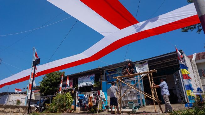 Sejumlah warga bergotong royong memasang kain merah putih di Perumahan Mutiara Tragung, Kecamatan Kandeman, Kabupaten Batang, Jawa Tengah, Senin (1/8/2022). [ANTARA FOTO/Harviyan Perdana Putra/nym]