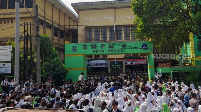 Para alumni SMPN 6 Kota Bekasi melakukan aksi demo di depan gerbang sekolah terkait dugaan kasus pelecehan seksual yang dilakukan petugas administrasi (Suara.com/Danan Arya)