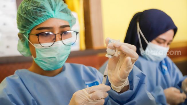 Officers take a booster vaccine injection at the Pulogadung Youth Center, East Jakarta, Tuesday (2/8/2022). [Suara.com/Alfian Winanto]