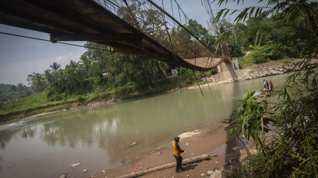 Warga melihat kondisi jembatan yang rusak di Desa Haurgajrug, Lebak, Banten, Selasa (2/8/2022). ANTARA FOTO/Muhammad Bagus Khoirunas
