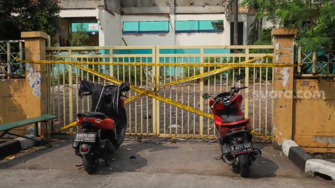 Garis polisi terpasang di pintu pagar Gelanggang Olahraga (GOR) Mampang setelah peristiwa robohnya tembok proyek revitalisasi di Pela Mampang, Jakarta Selatan, Selasa (2/8/2022). [Suara.com/Alfian Winanto]