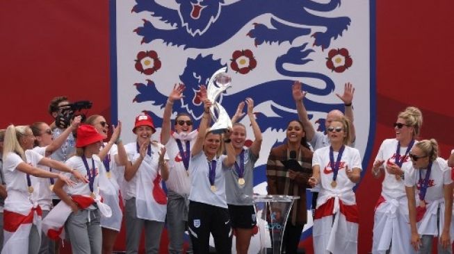 Pelatih Tim Wanita Inggris Sarina Wiegman mengangkat trofi di samping para pemain Inggris saat pesta kemenangan di Trafalgar Square di London tengah pada 1 Agustus 2022, sehari setelah mereka mengalahkan Jerman 2-1 untuk memenangkan turnamen sepak bola Euro 2022 Wanita.Hollie Adams / AFP