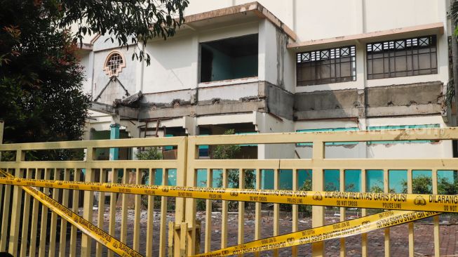 Garis polisi terpasang di pintu pagar Gelanggang Olahraga (GOR) Mampang setelah peristiwa robohnya tembok proyek revitalisasi di Pela Mampang, Jakarta Selatan, Selasa (2/8/2022). [Suara.com/Alfian Winanto]