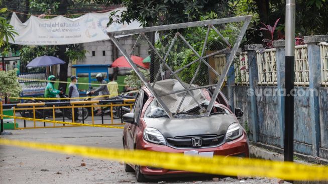 Sebuah mobil tertimpa besi akibat robohnya tembok proyek revitalisasi Gelanggang Olah Raga (GOR) Mampang di Pela Mampang, Jakarta Selatan, Selasa (2/8/2022). [Suara.com/Alfian Winanto]