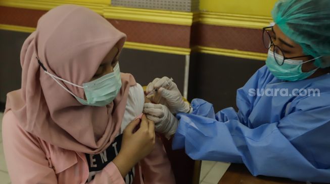 Os profissionais de saúde recebem a segunda injeção de vacina de reforço no Pulogadung Youth Center, East Jakarta, terça-feira (8/2/2022). [Suara.com/Alfian Winanto]