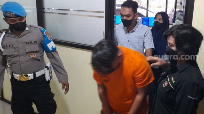 Tersangka D (tengah) pelecehan seksual di SMPN 6 saat dibawa anggota kepolisian untuk mengikuti rilis Di Polres Metro Bekasi Kota, Selasa, (2/08/2022) (Suara.com/Danan Arya)