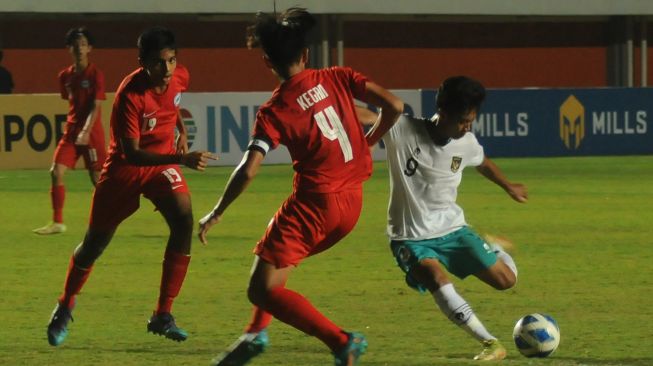 Pesepak bola Timnas Indonesia U-16 Muhammad Kafiatur (kanan) menendang bola di tengah hadangan pesepak bola Timnas Singapura U-16 Sahoo Garv (kiri) dan Kegan Phang (tengah) pada pertandingan AFF U-16 2022 di Stadion Maguwoharjo, Depok, Sleman, D.I Yogyakarta, Rabu (3/8/2022). ANTARA FOTO/Aloysius Jarot Nugroho