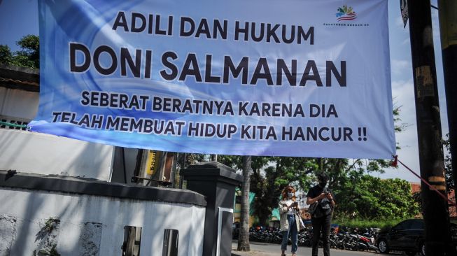 Warga berjalan di samping spanduk untuk terdakwa kasus penipuan investasi opsi biner Quotex Doni M. Taufik alias Doni Salmanan yang tengah menjalani sidang dakwaan di Pengadilan Negeri Bale Bandung, Baleendah, Kabupaten Bandung, Jawa Barat, Kamis (4/8/2022). ANTARA FOTO/Raisan Al Farisi