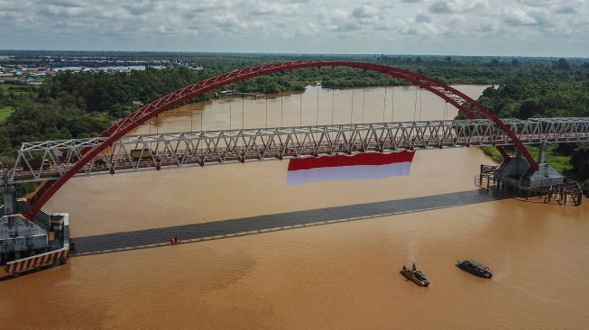 Foto udara sebuah bendera merah putih dibentangkan di Jembatan Kahayan, Palangka Raya, Kalimantan Tengah, Sabtu (6/8/2022). ANTARA FOTO/Makna Zaezar