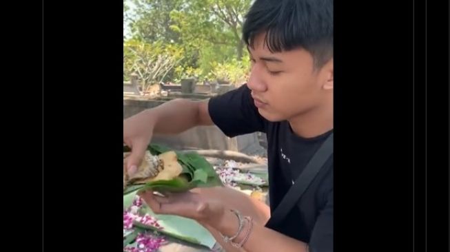 Viral Pemuda Makan Sesajen di Kuburan dengan Lahap, Warganet: Berani Banget