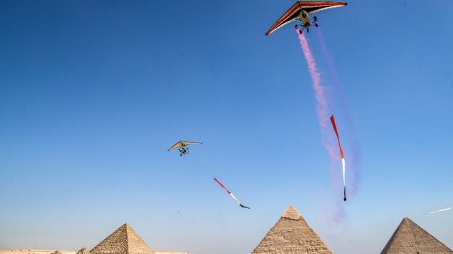 Pesawat bermanuver saat acara Pyramids Air Show 2022 di dataran tinggi Piramida Giza, Mesir, Rabu (3/8/2022). [Mahmoud Khaled / AFP]
