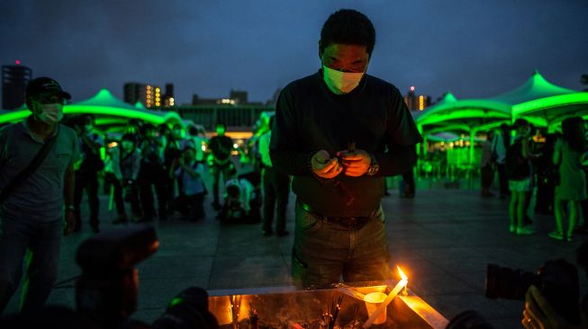 Pengunjung berdoa di depan tugu peringatan di Taman Peringatan Perdamaian Hiroshima di Hiroshima, Jepang, Sabtu (6/8/2022). [Philip FONG / AFP]