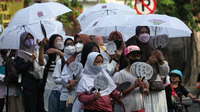 Warga dari Asosiasi Ibu Menyusui Indonesia (AIMI) Jawa Timur melakukan Aksi Payung Putih di Hari Bebas Kendaraan Bermotor atau 'Car Free Day' Jalan Darmo, Surabaya, Jawa Timur, Minggu (7/8/2022). [ANTARA FOTO/Didik Suhartono/nym]