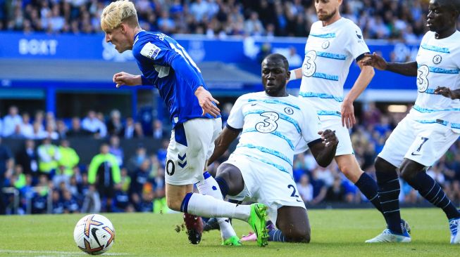 Gelandang Everton Anthony Gordon (kiri) ditekel oleh bek Chelsea Kalidou Koulibaly (tengah) ketika membawa bola saat pertandingan sepak bola Liga Premier Inggris antara Everton dan Chelsea di Stadion Goodison Park, Liverpool, Inggris, Sabtu (6/8/2022). [Lindsey Parnaby / AFP]