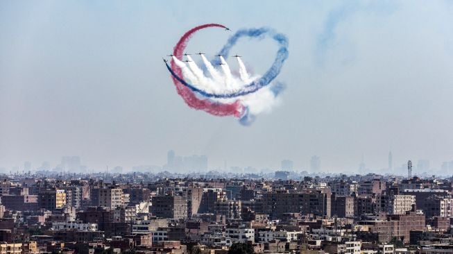 Pesawat K-8E Karakorum dari tim aerobatik Angkatan Udara Mesir 'Silver Stars' bermanuver saat acara Pyramids Air Show 2022 di dataran tinggi Piramida Giza, Mesir, Rabu (3/8/2022). [Mahmoud Khaled / AFP]