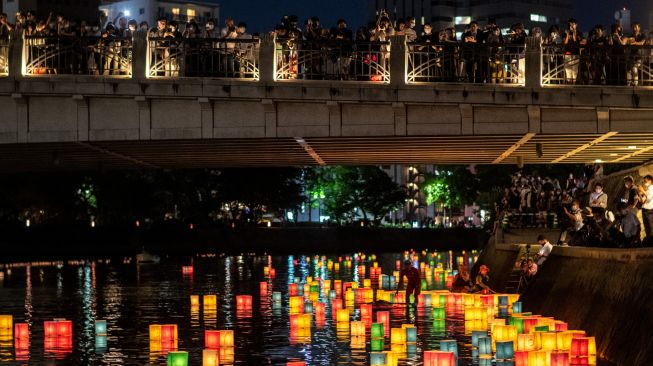 Warga melihat lentera kertas di Sungai Motoyasu untuk memperingati 77 tahun serangan bom atom di samping kubah bom atom, Hiroshima, Jepang, Sabtu (6/8/2022). [Philip FONG / AFP]
