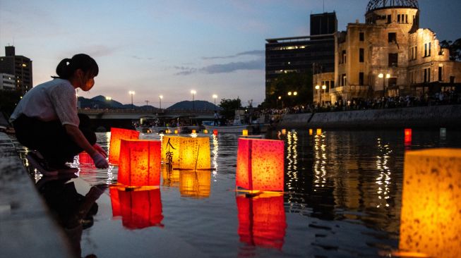 Warga melepas lentera kertas di Sungai Motoyasu untuk memperingati 77 tahun serangan bom atom di samping kubah bom atom, Hiroshima, Jepang, Sabtu (6/8/2022). [Philip FONG / AFP]