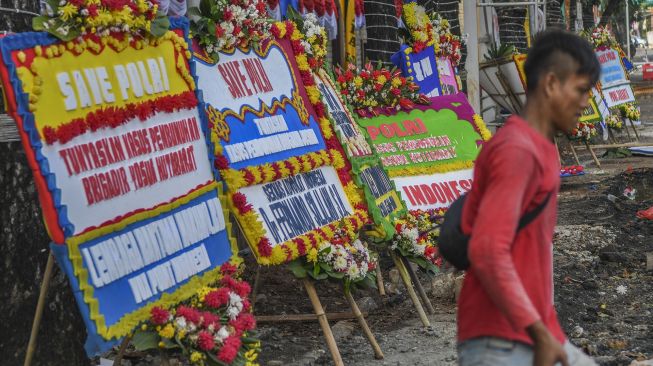 Seorang warga melintas di depan Mabes Polri yang dipenuhi karangan bunga di Jalan Trunojoyo, Jakarta, Senin (8/8/2022). ANTARA FOTO/Galih Pradipta