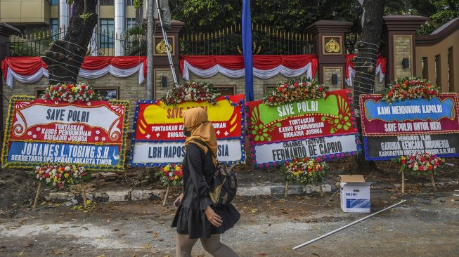 Seorang warga melintas di depan Mabes Polri yang dipenuhi karangan bunga di Jalan Trunojoyo, Jakarta, Senin (8/8/2022). ANTARA FOTO/Galih Pradipta