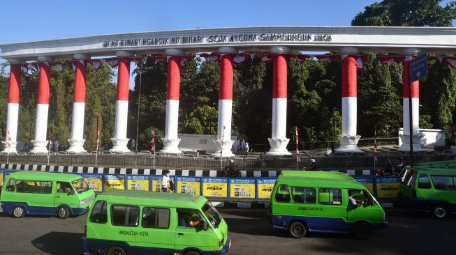 Sejumlah angkot melintas di depan Lawang Salapan yang dibalut bendera Merah Putih di jalan Otista, Kota Bogor, Jawa Barat, Senin (8/8/2022). ANTARA FOTO/Arif Firmansyah