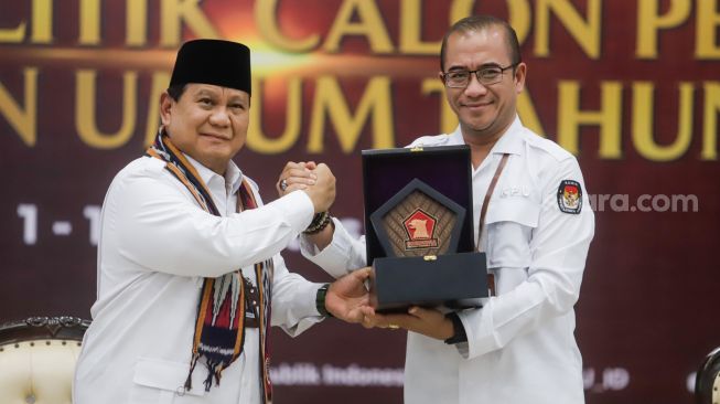 Ketua Komisi Pemilihan Umum (KPU) Hasyim Asy'ari (kanan) menerima cinderamata dari Ketua Umum Partai Gerakan Indonesia Raya (Gerindra) Prabowo Subianto saat Pendaftaran Partai Politik Calon Peserta Pemilu tahun 2024 di Kantor KPU, Jakarta Pusat, Senin (8/8/2022). [Suara.com/Alfian Winanto]