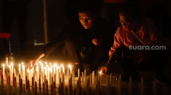 Peserta menyalakan lilin saat aksi tiga ribu lilin dan doa bersama untuk Alm Brigadir Nofriansyah Yosua Hutabarat di Taman Ismail Marzuki, Jakarta Pusat, Senin (8/8/2022). [Suara.com/Alfian Winanto]