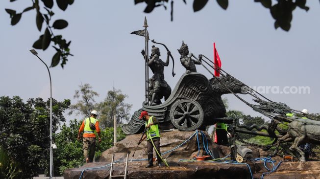 Pekerja membersihkan patung Arjuna Wijaya atau yang lebih dikenal sebagai patung kuda di jalan Medan Merdeka Barat, Jakarta Barat, Selasa (9/8/2022). [Suara.com/Alfian Winanto]