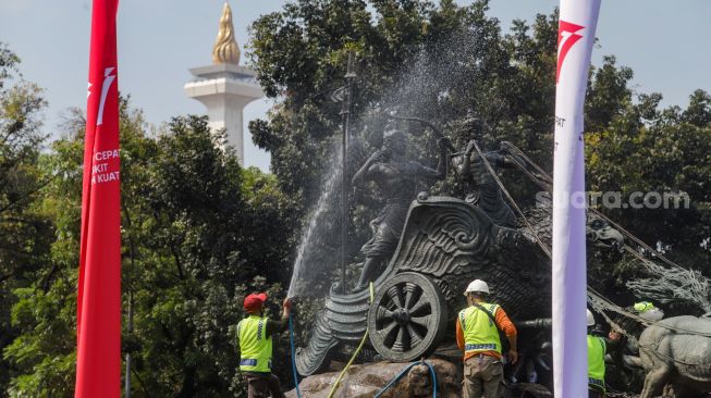 Pekerja membersihkan patung Arjuna Wijaya atau yang lebih dikenal sebagai patung kuda di jalan Medan Merdeka Barat, Jakarta Barat, Selasa (9/8/2022). [Suara.com/Alfian Winanto]