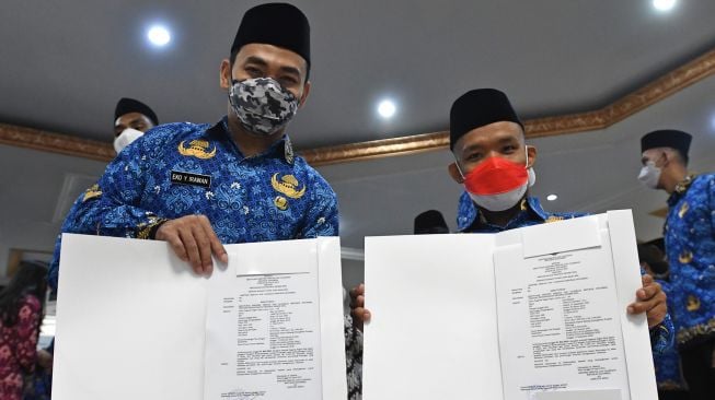 Lifter Eko Yuli Irawan (kiri) dan perenang difabel Aris Wibawa (kanan) menunjukkan surat keputusan Menteri Pemuda dan Olahraga (Menpora) tentang pengangkatan mereka sebagai Pegawai Negeri Sipil (PNS) di Kemenpora, Jakarta, Rabu (10/8/2022). ANTARA FOTO/Aditya Pradana Putra
