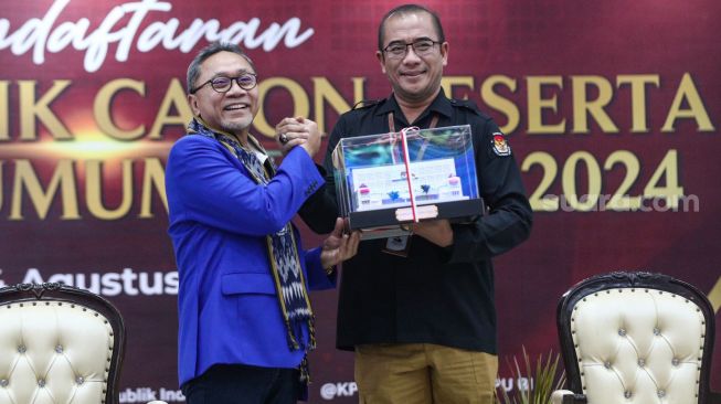 Ketua Komisi Pemilihan Umum (KPU) Hasyim Asy'ari (kanan) memberikan cinderamata kepada Ketua Umum Partai Amanat Nasional (PAN) Zulkifli Hasan saat Pendaftaran Partai Politik Calon Peserta Pemilu tahun 2024 di Kantor KPU, Jakarta Pusat, Rabu (10/8/2022). [Suara.com/Alfian Winanto]